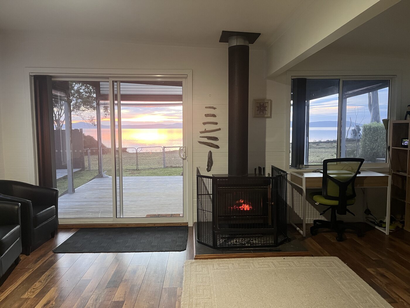Wood heater lit at dusk with bay sunset through the sliding doors