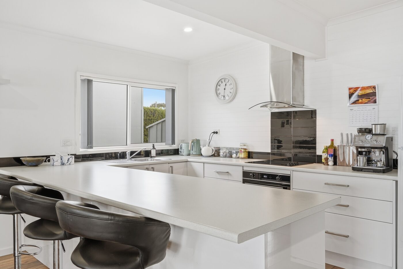 Kitchen with breakfast bar, cooktop, and coffee machine