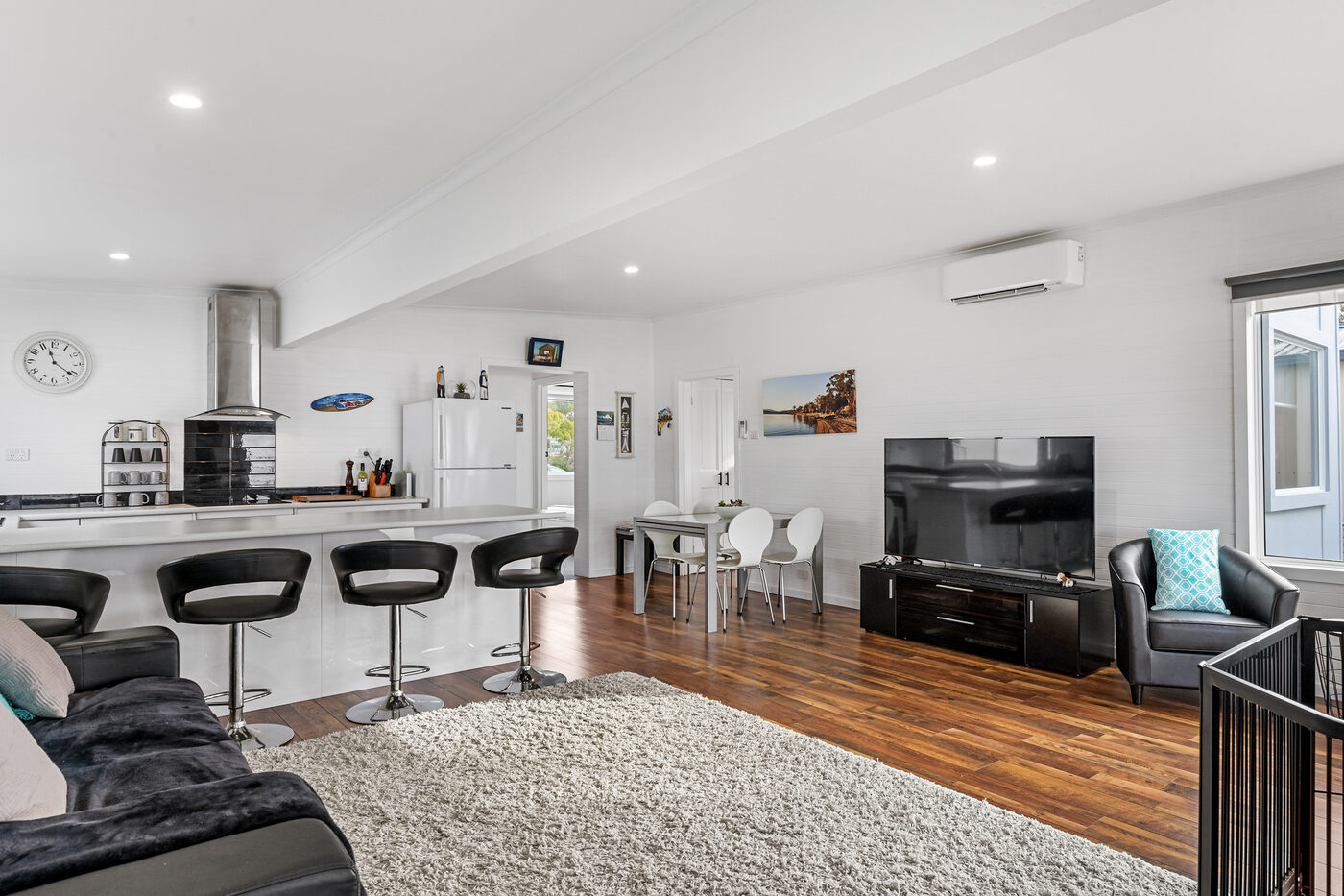 Living area with sofa, dining table, and reverse-cycle unit