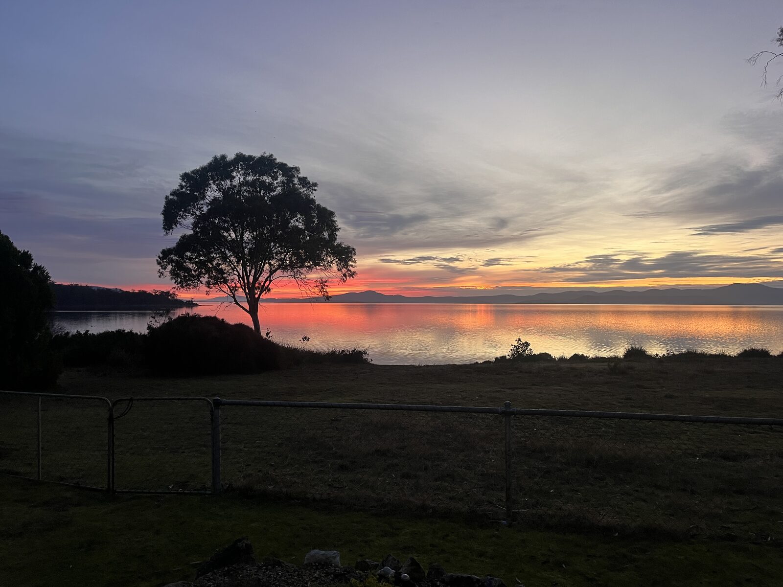 Orange sunset reflected across calm bay water